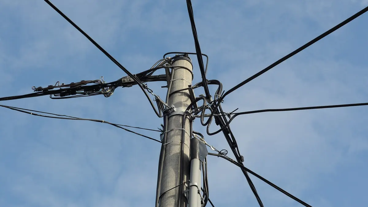 Poste de energia com fios elétricos contra o céu azul