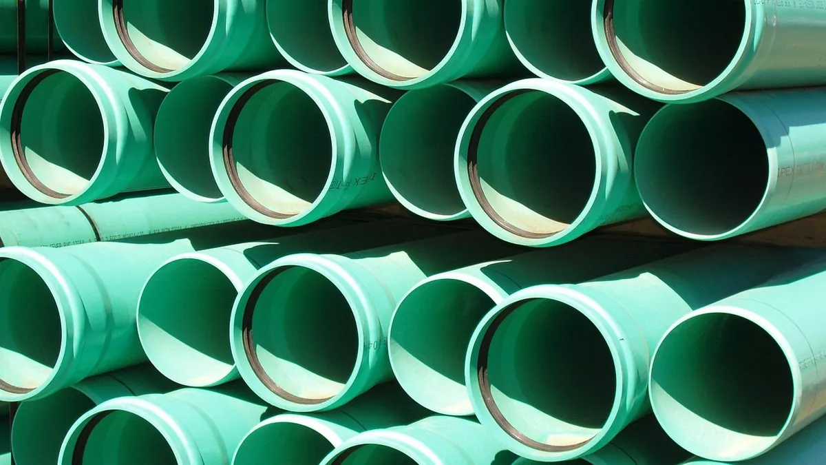 Tubos de PVC verdes empilhados em obra